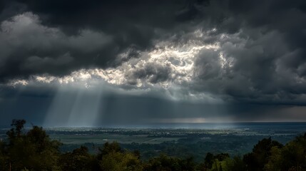 Fototapeta premium Dramatic stormy landscape with sun rays piercing through dark clouds