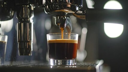 Close-up of espresso machine pouring fresh, dark coffee into a glass