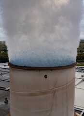 Industrial Cooling Tower Emitting Steam on Cloudy Day