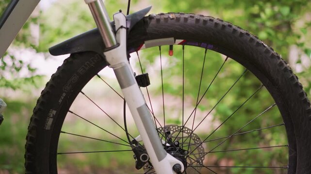 Forest Trail Scene With Bike Wheel, Suspension Fork And Knobby Tire On Mountain Bike, Detailed View Of Mountain Bike Front Wheel With Textured Tire And Suspension In Forest Setting