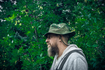 The guy with the beard is standing in the woods