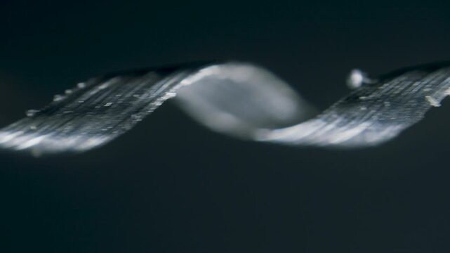 Titanium metal scrap shavings in spiral form under microscope on black background