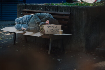 Homeless man sleeping on park bench needing food