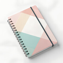 Spiral-bound notebook with a modern geometric pattern in pink, blue, and white, featuring an elastic closure band on a white background.