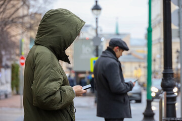 People using smartphones on a street. Woman and man in winter city