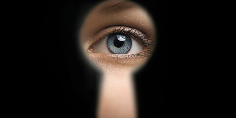 Blue eye peeking through dark keyhole