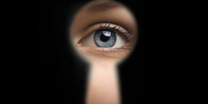 Blue eye peeking through dark keyhole
