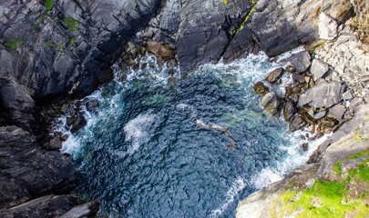 Aerial View of Rocky Coastline With Blue Water and Waves Crashing, in Ireland