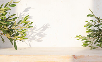 Empty wooden table on abstract plaster wall texture background with light shadows of tropical plant leaves