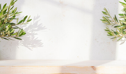 Background for product montage with bleached wooden table in dappled light shadows from window and tropical plant branches on abstract wall