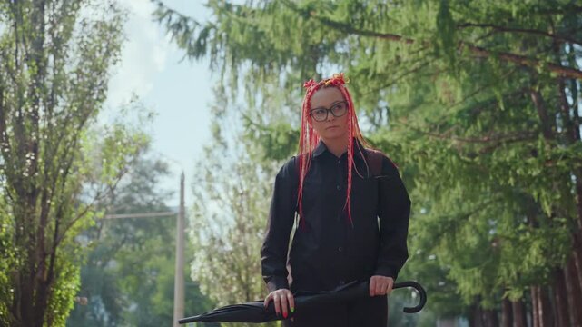 woman with bike, caucasian female holding bicycle in peaceful sunlit outdoor setting, contemplative woman with glasses and vibrant red dreadlocks stands by her bicycle in tranquil park