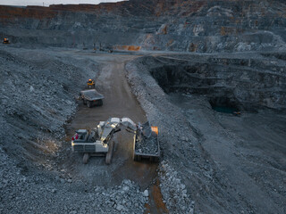 Aerial view Excavation and mining truck transport at large open pit mine at dusk