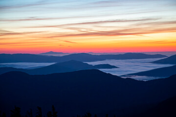View from Mount Gosford, Quebec, Canada of Mountains Silhouettes Against a Vibrant Sunrise Sky With Fog
