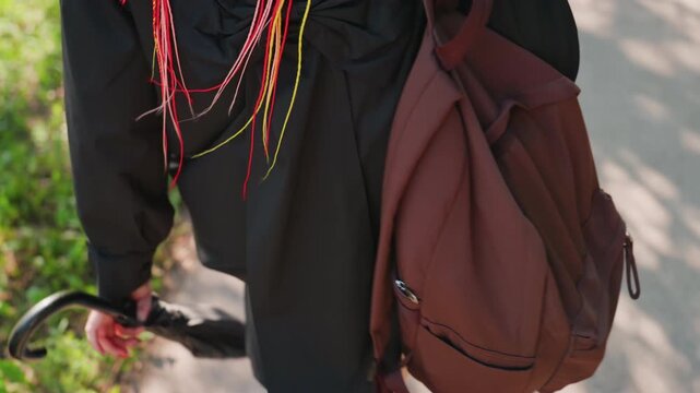 casual city walk scene, person with vibrant braids and accessories, closeup of commuter carrying accessories during day, everyday scene of traveler with colorful hair and essential gear