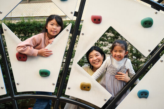 Japanese mother and daughters playing on climbing wall
