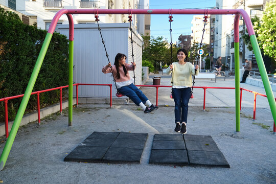 Japanese mother daughter enjoying swing set in park