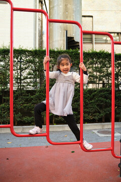 Japanese girl playing on red climbing frame