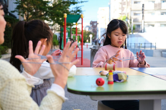 Japanese family playing cat's cradle string game outdoors