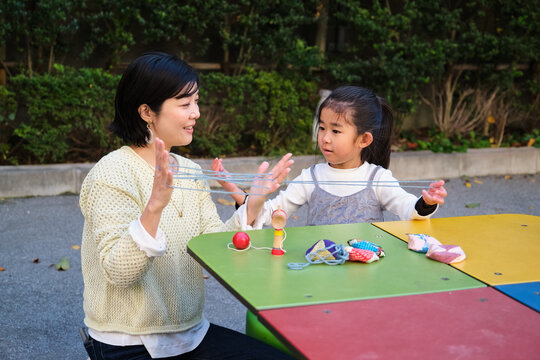 Japanese mother and daughter playing traditional games outdoors