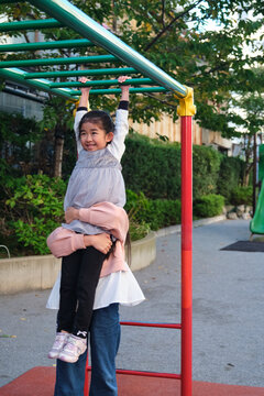 Japanese girl playing on monkey bars with help