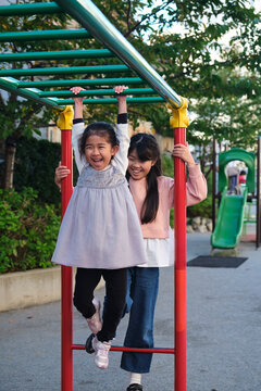 Happy Japanese girls playing on monkey bars