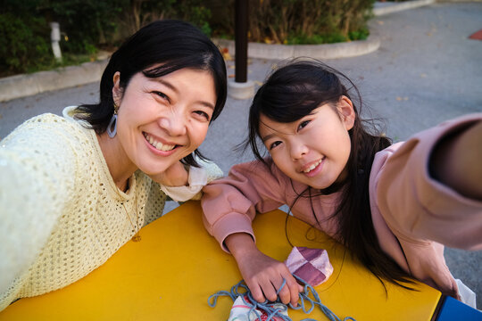 Japanese mother and daughter taking happy outdoor selfie