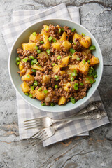 Ground Beef and Potato Stir-Fry closeup on the plate on the table. Vertical top view from above