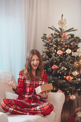Smiling Girl In Pajamas Beside Christmas Decorated Tree