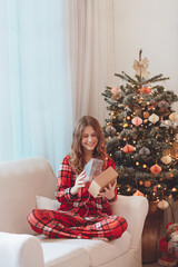 Smiling Girl In Pajamas Beside Christmas Decorated Tree