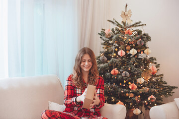 Smiling Girl In Pajamas Beside Christmas Decorated Tree