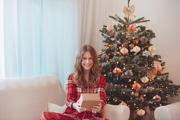 Smiling Girl In Pajamas Beside Christmas Decorated Tree