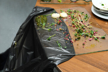 Dirty dishes piled high after a banquet, with food leftovers and scraps scattered on a table, showcasing the aftermath of a lively reception with vibrant colors and textures