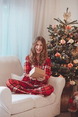 Smiling Girl In Pajamas Beside Christmas Decorated Tree