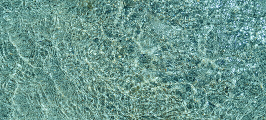 Crystal clear water surface, ripple water in the sea with sun reflection