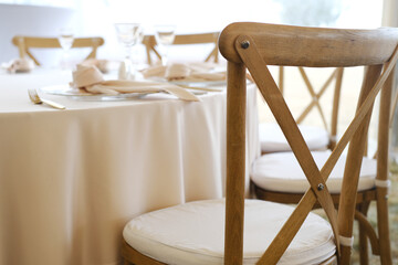 Elegant wooden chairs arranged around a beautifully set wedding banquet table with soft linens and glassware, creating an inviting atmosphere for celebration and joy