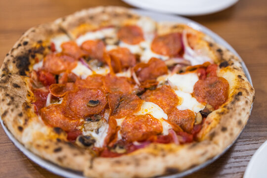 Hot spicy sausage pizza served on wooden plate