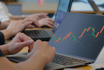 上昇トレンドを示す株価チャートを分析するビジネスパーソン