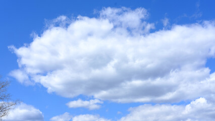 White fluffy clouds in blue sky with soft sunlight illuminating the clouds and clear atmosphere during daytime with no visible objects or structures in the scene