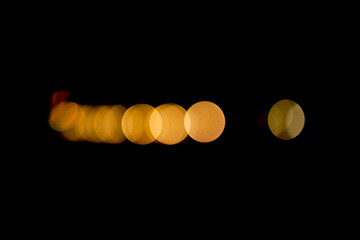 Defocused golden lights from a decorative garland form overlapping bokeh circles on a black