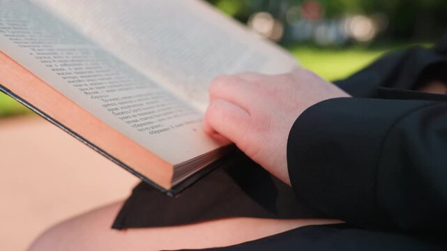 book corner lift, fingertip turning page in outdoor setting, reading outdoors with pages gently lifted by fingertips, beautiful sunlight illuminating person lifting page corner of book outside