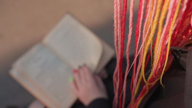 detailed artistic photograph, closeup of vibrant braided book, intimate shot featuring colorful braided pages and yarn, focused image of hand flipping through decorative vintage book