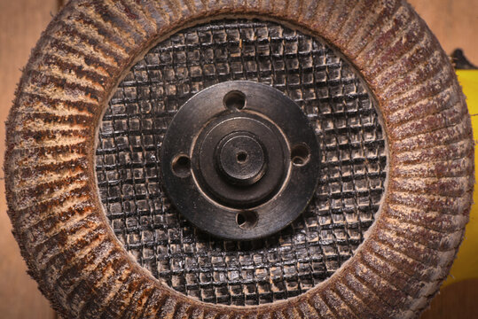 Angle grinder with abrasive flap disc on wooden flat lay background.