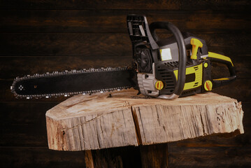 Naklejka premium Chainsaw with mounted guide bar and cutting chain and cut firewood logs on wooden workbench table background. Front view.
