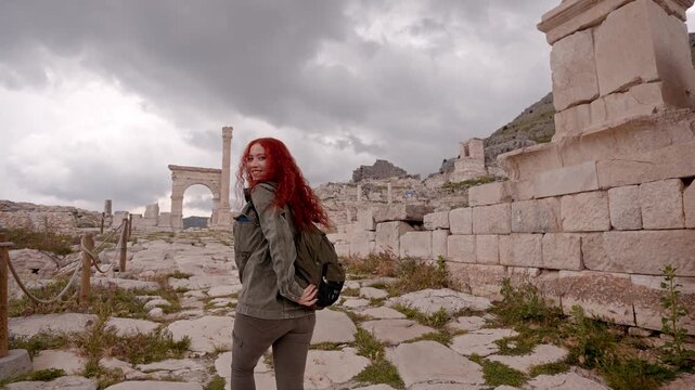 A female traveler looking at the camera while walking through the ruins of Sagalassos Ancient City in Burdur, Turkey. Roman-era heritage reflecting exploration, tourism, cultural travel, and travel li