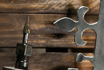 Electric straight grinder with metal burr bit cutting steel crown element top view on dark workshop close up background with copy space.