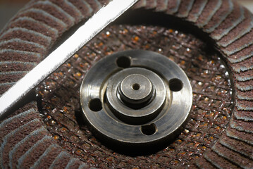 Close up view of abrasive flap disc metal hub and grinding wheel surface during metalworking process on industrial workshop top view background.