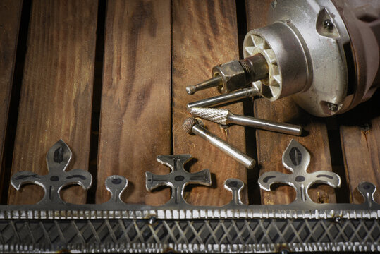 Electric straight grinder with metal milling cutter attachments for metalworking on wooden workbench table close up background.