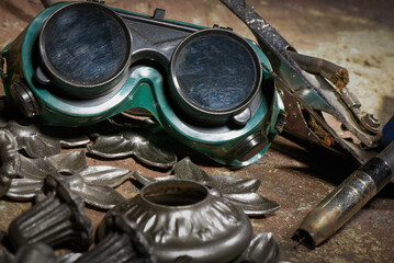 Floor standing wrought iron candelabra and electric welding torch concept during manufacturing process in blacksmith workshop.