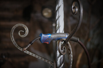Floor standing wrought iron candelabra and electric welding torch concept during manufacturing process in blacksmith workshop.