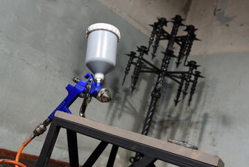 Blue HVLP spray gun nozzle with trigger and metal air cap close up on neutral background.